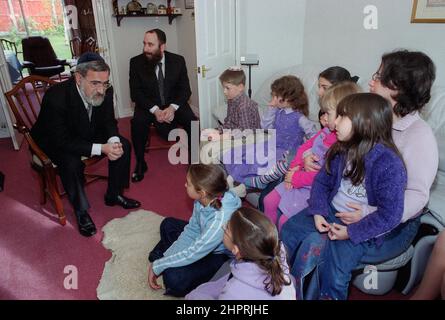 Le Grand Rabbin Jonathan Sacks a été l'invité d'honneur pour la célébration du 25th anniversaire de la Congrégation hébraïque de Solihull. Au cours de sa visite, il a rencontré des enfants dans le salon d'une famille de la congrégation. Il parle officieusement aux jeunes enfants juifs de leur travail réalisé au Cheder de la synagogue (salle de classe), regarde le ministre de la congrégation, Rabbi Yehuda Pink. Il a pris la parole pendant le service religieux le 27th octobre 2002.le maire de Solihull Cllr. Kate Wild a assisté et a reçu un bouquet de l'élève de Cheder de 13 ans Zipporah Gershon Banque D'Images