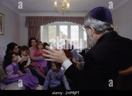 Le Grand Rabbin Jonathan Sacks a été l'invité d'honneur pour la célébration du 25th anniversaire de la Congrégation hébraïque de Solihull. Au cours de sa visite, il a rencontré des enfants dans le salon d'une famille de la congrégation. Il parle officieusement aux jeunes enfants juifs de leur travail réalisé au Cheder de la synagogue (salle de classe), regarde le ministre de la congrégation, Rabbi Yehuda Pink. Il a pris la parole pendant le service religieux le 27th octobre 2002.le maire de Solihull Cllr. Kate Wild a assisté et a reçu un bouquet de l'élève de Cheder de 13 ans Zipporah Gershon Banque D'Images