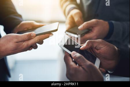 Il est essentiel de rester au courant dans un monde connecté. Photo d'un groupe d'hommes d'affaires méconnus utilisant leur téléphone portable en synchronicité. Banque D'Images