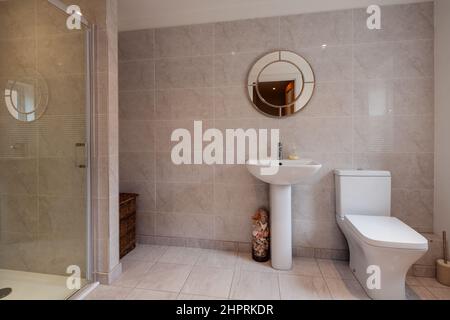 Swavesey, Cambridgeshire - août 22 2018: Salle de douche moderne à l'aspect traditionnel avec murs carrelés, cabine de douche à façade en verre, toilettes et piédestal Banque D'Images