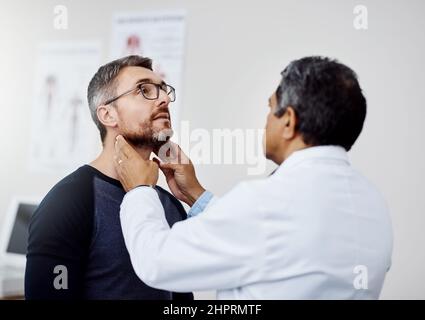 J’ai juste besoin que vous ayez une profonde respiration pour moi. Prise de vue d'un médecin homme mature et confiant effectuant un examen médical d'un patient à l'intérieur d'un hôpital pendant la journée. Banque D'Images
