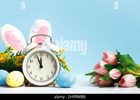 Composition de Pâques. Réveil œufs oreilles tulipes de lapin sur fond bleu. Banque D'Images