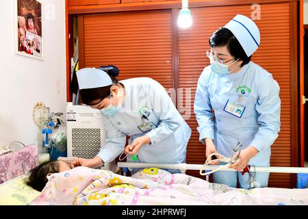 (220223) -- JINAN, le 23 février 2022 (Xinhua) -- l'infirmière Lian Ping (C) et Wang Chao(R) du troisième hôpital provincial de Shandong fournissent des soins porte-à-porte à un patient dans une zone résidentielle du district de Tianqiao, à Jinan City, dans la province de Shandong, en Chine orientale, le 23 février 2022. La province de Shandong a mis en place une plate-forme en ligne qui offre aux patients des soins infirmiers de porte à porte. Les patients qui se rétablissent à la maison ont maintenant l'accès pour demander les services de soins infirmiers en ligne.Un total de 176 établissements médicaux et environ 15 000 infirmières qualifiées et expérimentées se sont inscrits sur la plate-forme pour fournir des soins médicaux Banque D'Images