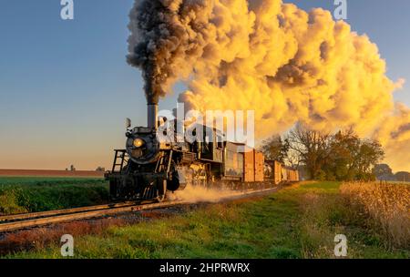 Ronks, Pennsylvanie, octobre 2020 - Une vue d'un train à vapeur de fret antique de fumée soufflant approchant à travers les arbres à Sunrise Banque D'Images