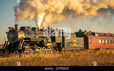 Ronks, Pennsylvanie, octobre 2020 - Une vue d'un train à vapeur passager antique de fumée qui s'approche à travers les arbres ar Sunrise Banque D'Images