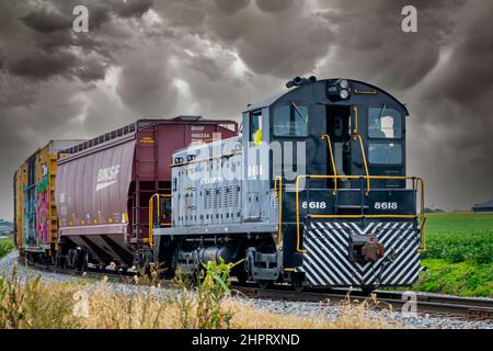 Ronks, Pennsylvanie, octobre 2020 - vue d'un train de marchandises diesel voyageant sur une seule piste avec des voitures Graffiti-ed alors qu'une tempête approche. Banque D'Images