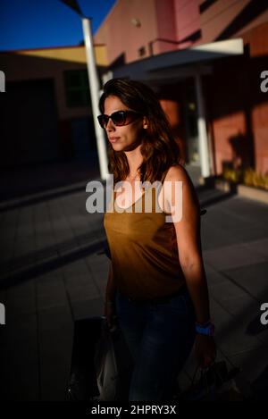 Une jeune femme attirante qui porte des sacs de shopping sort du centre commercial Banque D'Images