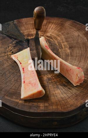 Vue en hauteur de la grande moelle osseuse de bœuf hachée avec un cale sur la moitié sur une souche en bois Banque D'Images