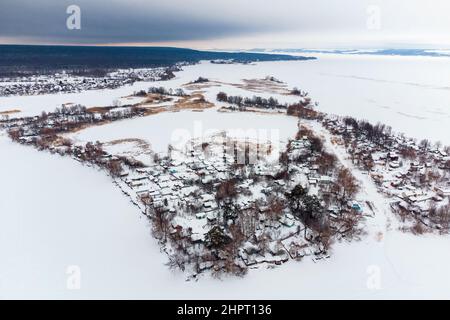 Vue aérienne du village au milieu de la baie gelée le jour d'hiver après la chute de neige Banque D'Images