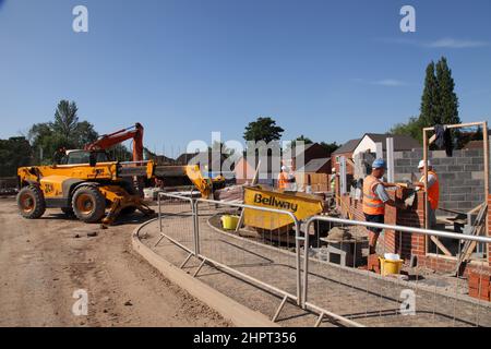 Des constructeurs et des couches de briques travaillent sur un site de construction Bellway Homes dans les West Midlands, en Angleterre, au Royaume-Uni Banque D'Images