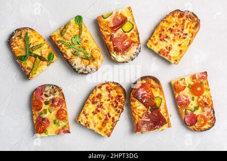 Tranches de pizza sur du pain avec du fromage et des ingrédients tels que le salami, le prosciutto, le jambon et les asperges Banque D'Images