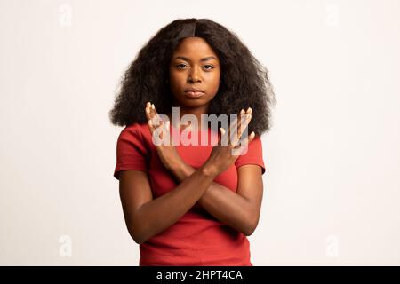 Portrait d'une jeune femme noire montrant un geste d'arrêt avec des mains croisées Banque D'Images