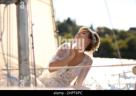 mariée sur un yacht à voile dans les rayons du soleil couchant Banque D'Images