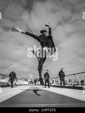 Image en noir et blanc d'un artiste martial, et danseur effectue un mouvement de ballet sur le Millennium Bridge à Londres. Banque D'Images