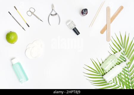 Soins des ongles. Poser à plat les outils de manucure ou de pédicure sur une table blanche avec des feuilles vertes. Banque D'Images