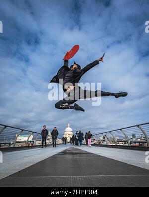 Un artiste martial et une danseuse effectuent des coups de pied élevés sur le Millennium Bridge à Londres. Banque D'Images