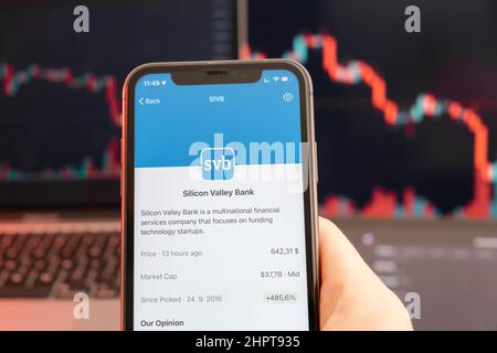 Silicon Valley Bank baisse du cours des actions sur le marché de négociation avec graphique à barres de tendance à la baisse sur le fond. Homme tenant un téléphone portable avec le logo de la société, février 2022, San Francisco, Etats-Unis. Banque D'Images