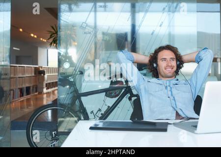 Se sentir détendu au bureau. Photo courte d'un jeune homme d'affaires à l'air détendu assis au bureau. Banque D'Images