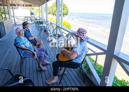 Tokomaru Bay Nouvelle-Zélande - février 4 2022; femmes maoris senior sur la véranda du pub local avec des masques covid, de la bière et de la guitare chantant et appréciant l'afte Banque D'Images