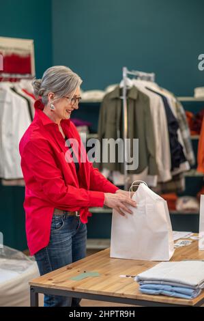 Bonne femme tenant un sac avec des vêtements sur une table Banque D'Images