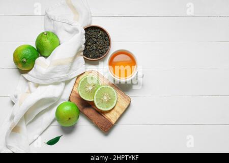 Composition avec tasse de thé, feuilles séchées et fruits mûrs bergamote sur fond de bois blanc Banque D'Images