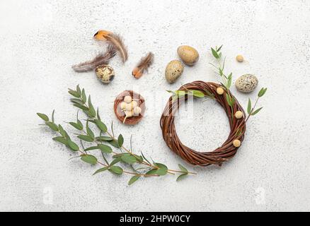 Composition avec couronne, branches d'eucalyptus, plumes et œufs de Pâques sur fond clair Banque D'Images