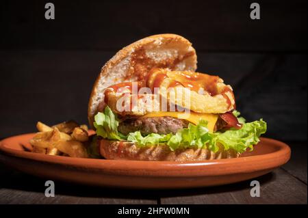 Hamburger de qualité supérieure avec rondelles d'oignon, fromage et sauce barbecue, servi avec des frites sur une assiette rustique. Photographie de haute qualité. Banque D'Images