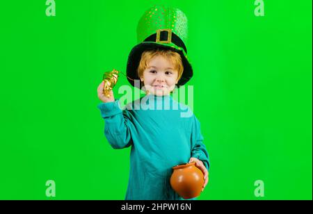 Enfant mignon avec pot d'or. Célébrations de la journée de Patrick. Petit garçon en chapeau Leprechaun. Pièces. Argent. Banque D'Images