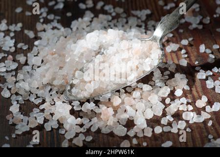 Un tas de sel dans une cuillère en métal sur fond sombre. Épices. Apport excessif de sel Banque D'Images