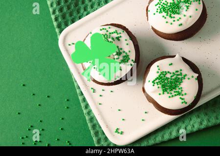 Des petits gâteaux faits maison ou un muffin au chocolat pour la Saint Patrick sur fond vert. Vue de dessus. Copier l'espace. Cupcake avec glaçage vert. Banque D'Images