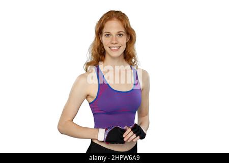 Athlète rouge féminin portant des gants d'entraînement et un débardeur. Femme sportive souriante pose sur fond blanc. Banque D'Images