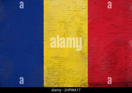 Photo plein cadre d'un drapeau de Roumanie recouvert d'intempéries peint sur un mur en brique plâtrée. Banque D'Images