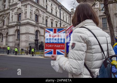 Londres, Royaume-Uni. 23rd février 2022. Un manifestant devant Downing Street détient un écriteau suggérant que la Russie finance le Parti conservateur. Des manifestants anti-conservateurs se sont rassemblés à Westminster alors que Boris Johnson était confronté à des QPM. Credit: Vuk Valcic/Alamy Live News Banque D'Images