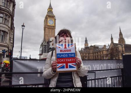 Londres, Royaume-Uni. 23rd février 2022. Un manifestant sur la place du Parlement tient un écriteau suggérant que la Russie finance le Parti conservateur. Des manifestants anti-conservateurs se sont rassemblés à Westminster alors que Boris Johnson était confronté à des QPM. Credit: Vuk Valcic/Alamy Live News Banque D'Images