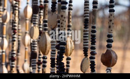 Gros plan de cordes de colliers africains faits de perles et de graines exposées sur un marché extérieur en Namibie. Arrière-plan flou ou flou Banque D'Images