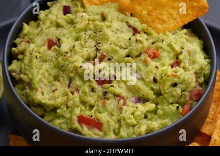 Gros plan sur une délicieuse sauce guacamole fraîche dans une assiette noire Banque D'Images