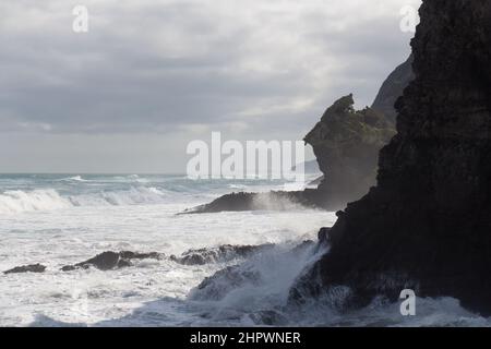 La vue du paysage marin avec un rocher incliné, des vagues et un ciel nuageux en arrière-plan, West Beach près d'Auckland, Nouvelle-Zélande. Banque D'Images