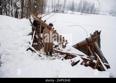 Budgam, Inde. 22nd févr. 2022. Un propriétaire inspecte sa maison endommagée dans un village de Bugam Chadoora. La vallée du Cachemire a subi de fortes chutes de neige, ce qui a conduit à la fermeture de routes dans les zones éloignées, outre le retard de plusieurs vols en provenance de l'aéroport de Srinagar. Les services ferroviaires locaux ont également été suspendus. Crédit : SOPA Images Limited/Alamy Live News Banque D'Images