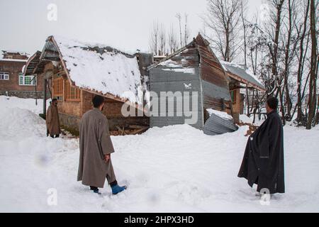 Budgam, Inde. 22nd févr. 2022. Les gens inspectent une maison endommagée au village de Bugam Chadoora. La vallée du Cachemire a subi de fortes chutes de neige, ce qui a conduit à la fermeture de routes dans les zones éloignées, outre le retard de plusieurs vols en provenance de l'aéroport de Srinagar. Les services ferroviaires locaux ont également été suspendus. Crédit : SOPA Images Limited/Alamy Live News Banque D'Images