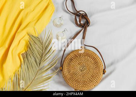 Chapeau de paille, robe jaune, sac de paille sur fond blanc. Tenue d'été tendance. Flat Lay avec des vêtements pour les vacances et les vacances. Banque D'Images