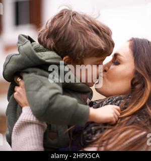 Donnez un baiser à votre mère. Photo d'une belle mère soulevant son jeune fils et lui donnant un baiser. Banque D'Images