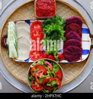 Incroyable nourriture de matière première colorée pour hamburger vegan de patate douce violette avec sauce tomate, salade, concombre, nourriture saine pour le petit déjeuner qui ri Banque D'Images