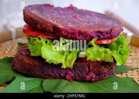 Délicieux hamburger végétalien de patate douce violette avec tomate, salade, nourriture saine pour le petit déjeuner que riche amidon, fibre Banque D'Images