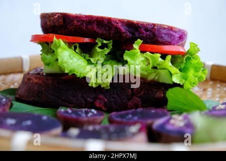 Délicieux hamburger végétalien de patate douce violette avec tomate, salade, nourriture saine pour le petit déjeuner que riche amidon, fibre Banque D'Images