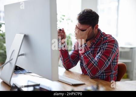 Besoin de plus d'énergie pour maintenir votre avantage. Photo d'un jeune designer décontracté tenant sa tête dans le désespoir. Banque D'Images