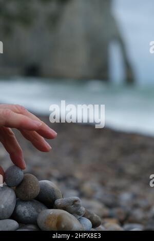 La main de femme empilant des rochers avec un fond de foyer doux Banque D'Images