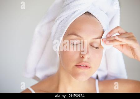 Nettoyage doux de sa peau. Gros plan d'une jeune femme attrayante avec ses cheveux enveloppés dans une serviette démaquillant. Banque D'Images
