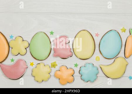 Biscuits de Pâques sur table en bois. Oeufs colorés, fleurs et un lapin. Banque D'Images