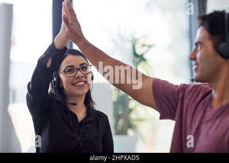 Toujours prouver une expérience de service client de qualité. Photo de deux agents de centre d'appels se donnant un haut cinq au bureau. Banque D'Images
