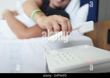 Un homme met le téléphone en position allongée dans le lit Banque D'Images